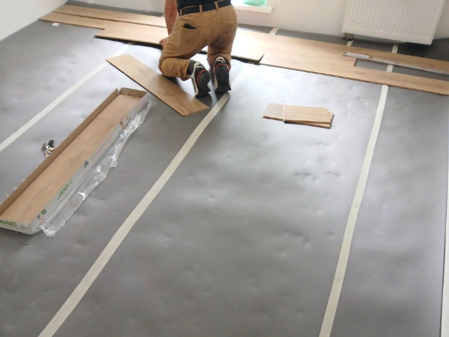 Handwerker verlegt Laminatdielen auf einer vorbereiteten Trittschalldämmung in Wetter (Hessen).