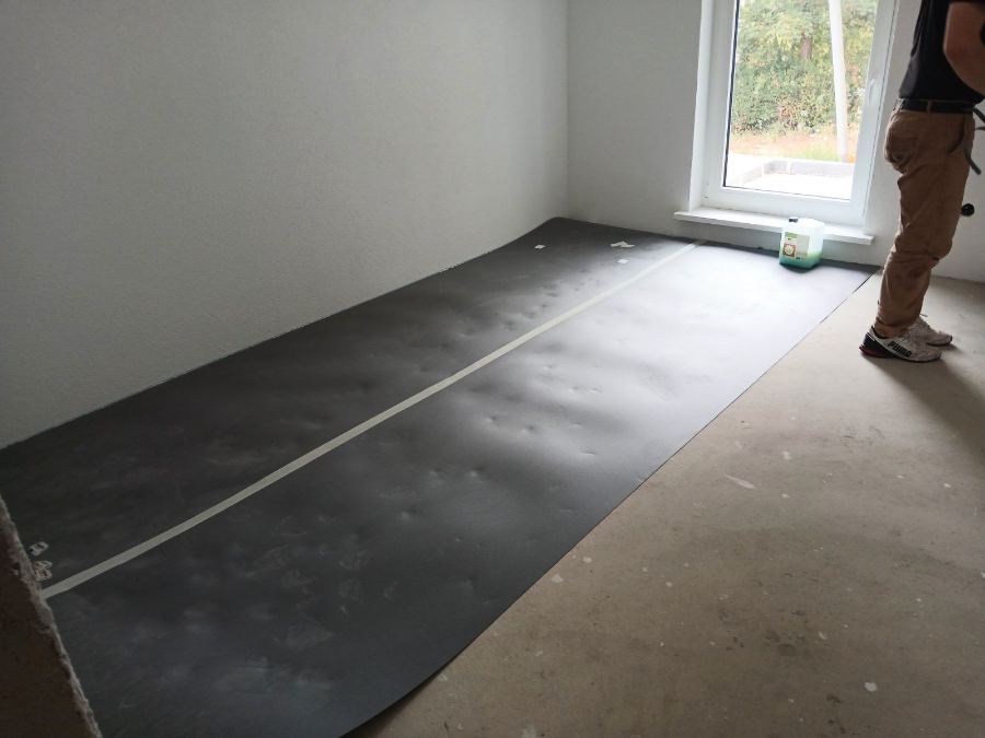 Ausgelegte und verklebte Trittschalldämmung als vorbereiteter Untergrund in einem Wohnraum.